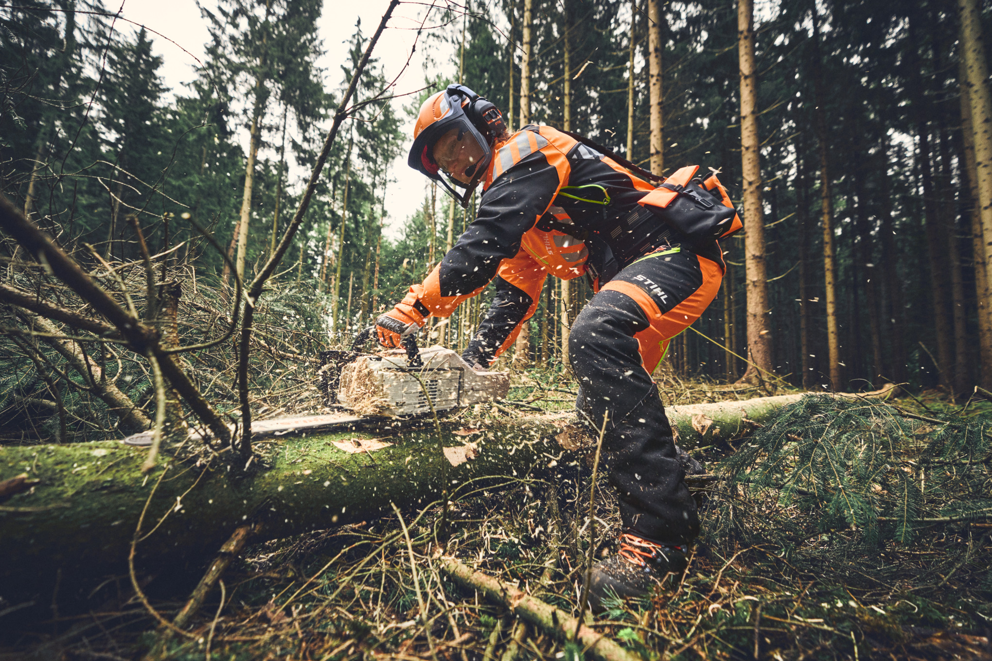 Lesní dělník při odvětvování akumulátorovou řetězovou pilou STIHL MSA 300 a s kompletními osobními ochrannými prostředky pro práci v lese 