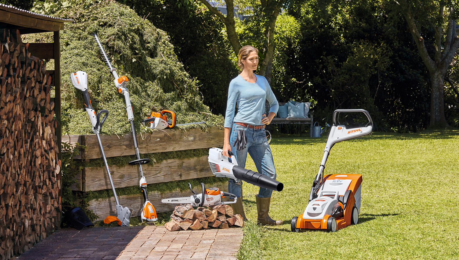 Žena stojící na zahradě s několika akumulátorovými produkty značky STIHL