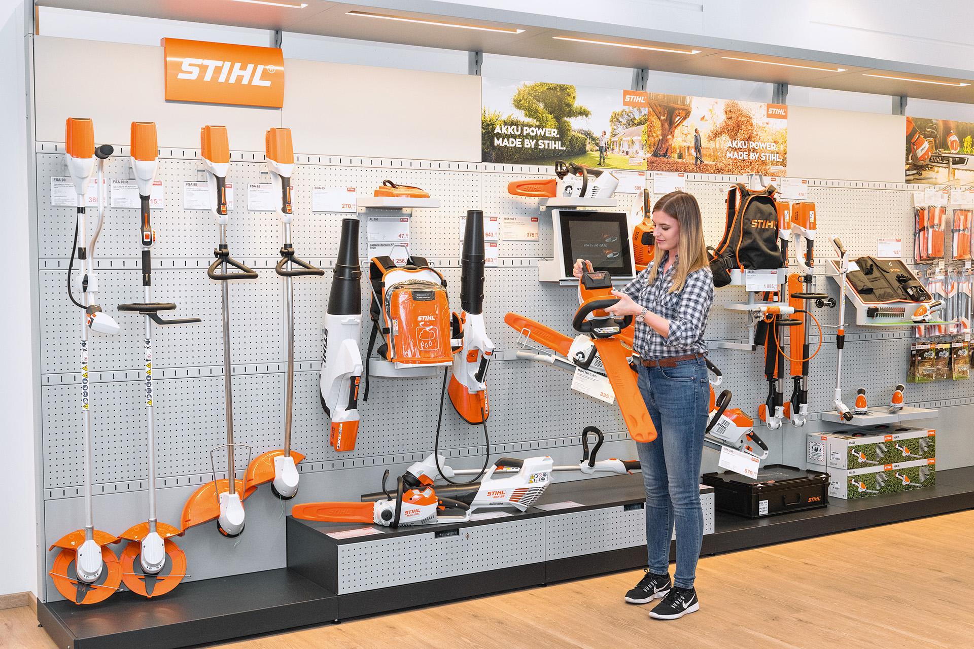 Mladá žena před prodejním pultem u specializovaného prodejce STIHL si chce zdarma vyzkoušet motorovou pilu STIHL