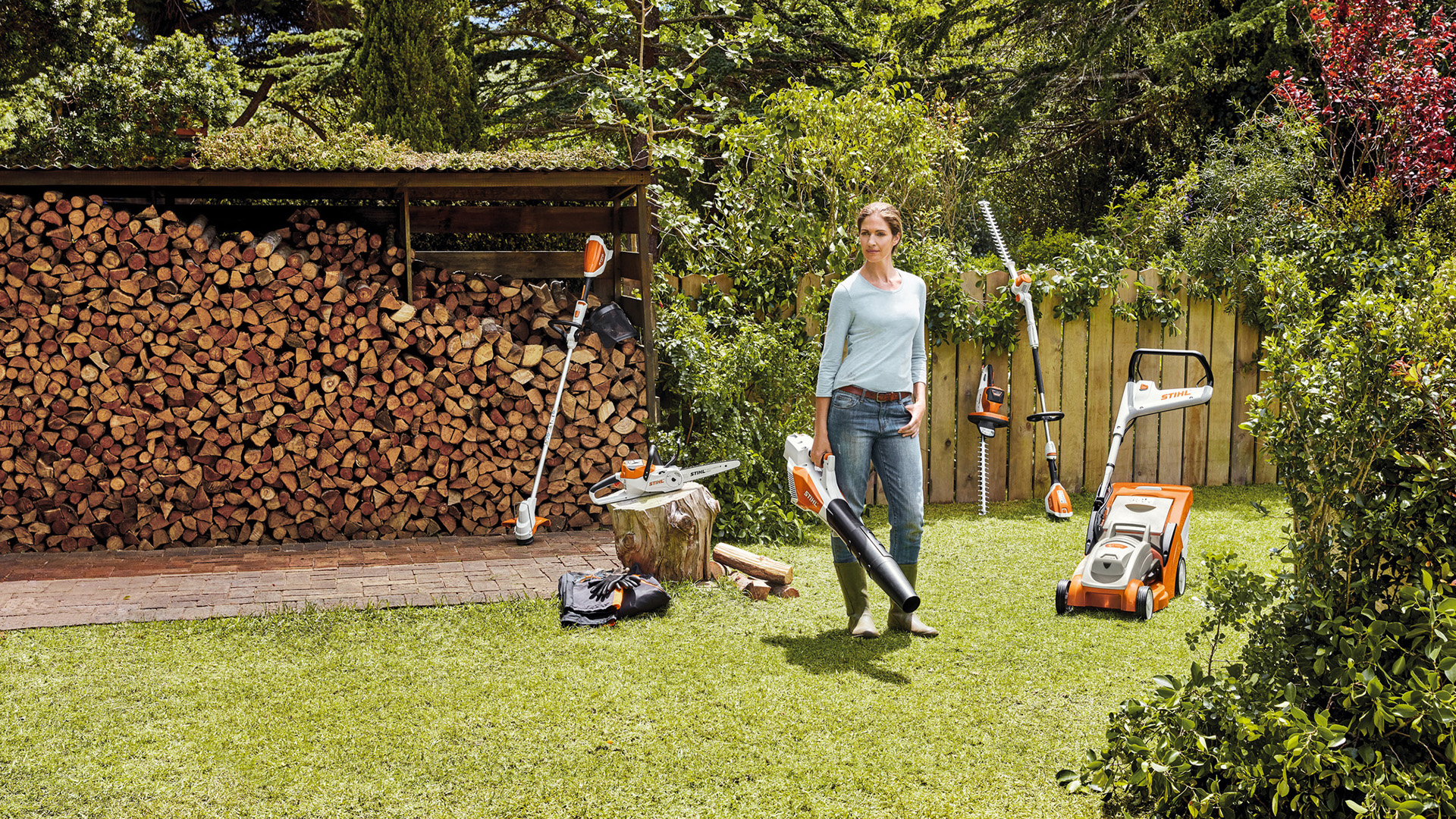 Žena stojí na zahradě před hromadou dřeva s nářadím z AK-Systému 