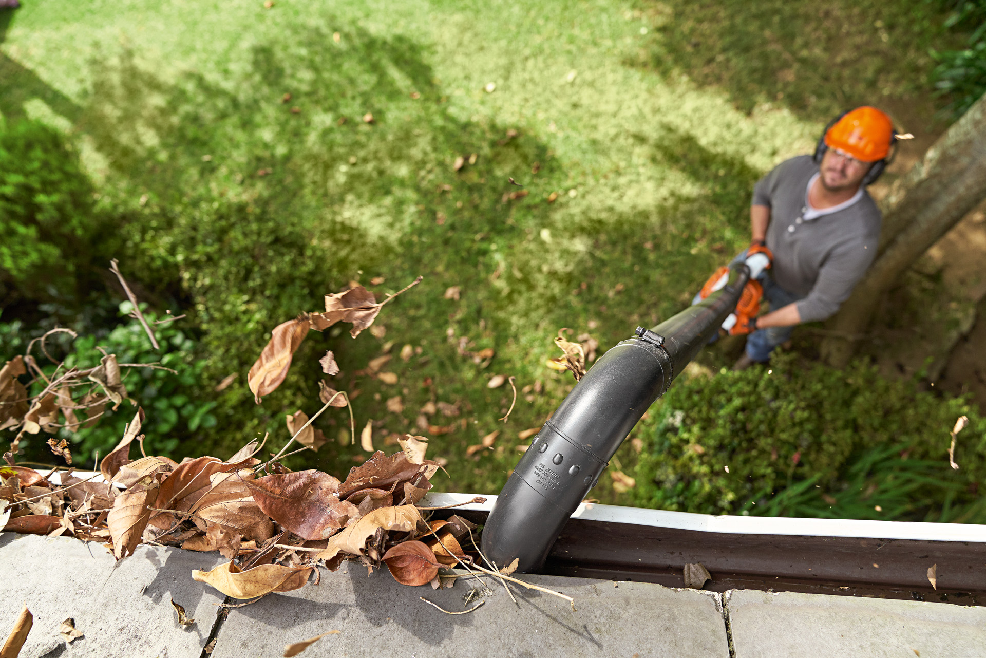 Muž čistí okapový žlab sadou STIHL k čištění okapových žlabů