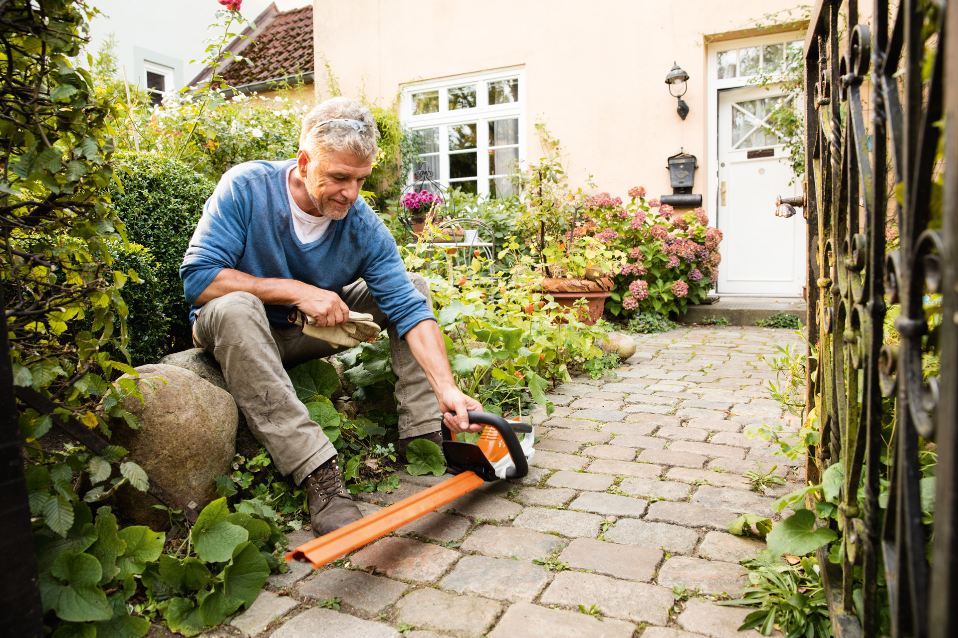 Muž před domem se zahradními nůžkami STIHL HSA 45 řady AI-Linie