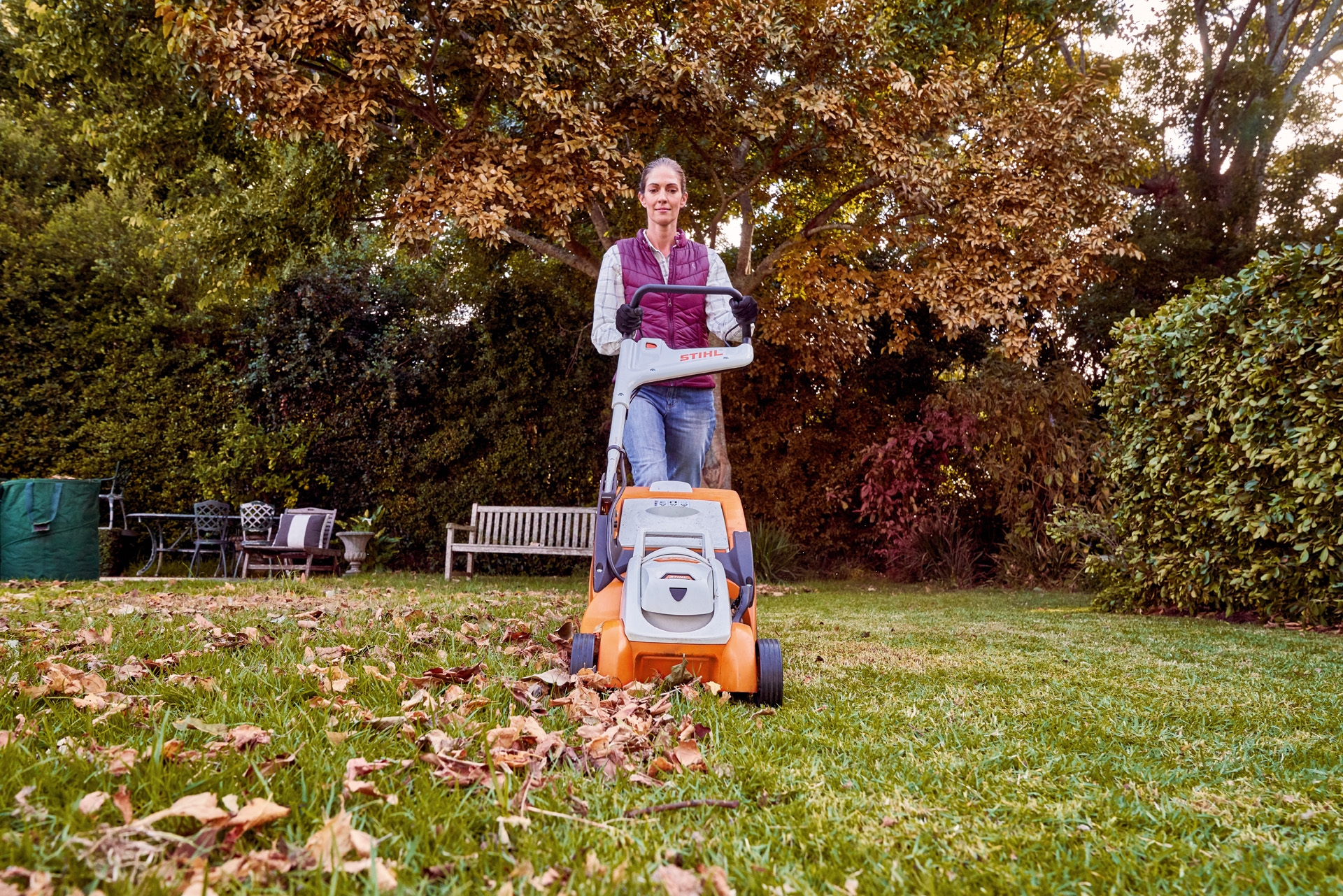 Žena používá k podzimní péči o trávník na zahradě akumulátorovou sekačku STIHL RMA 339 C