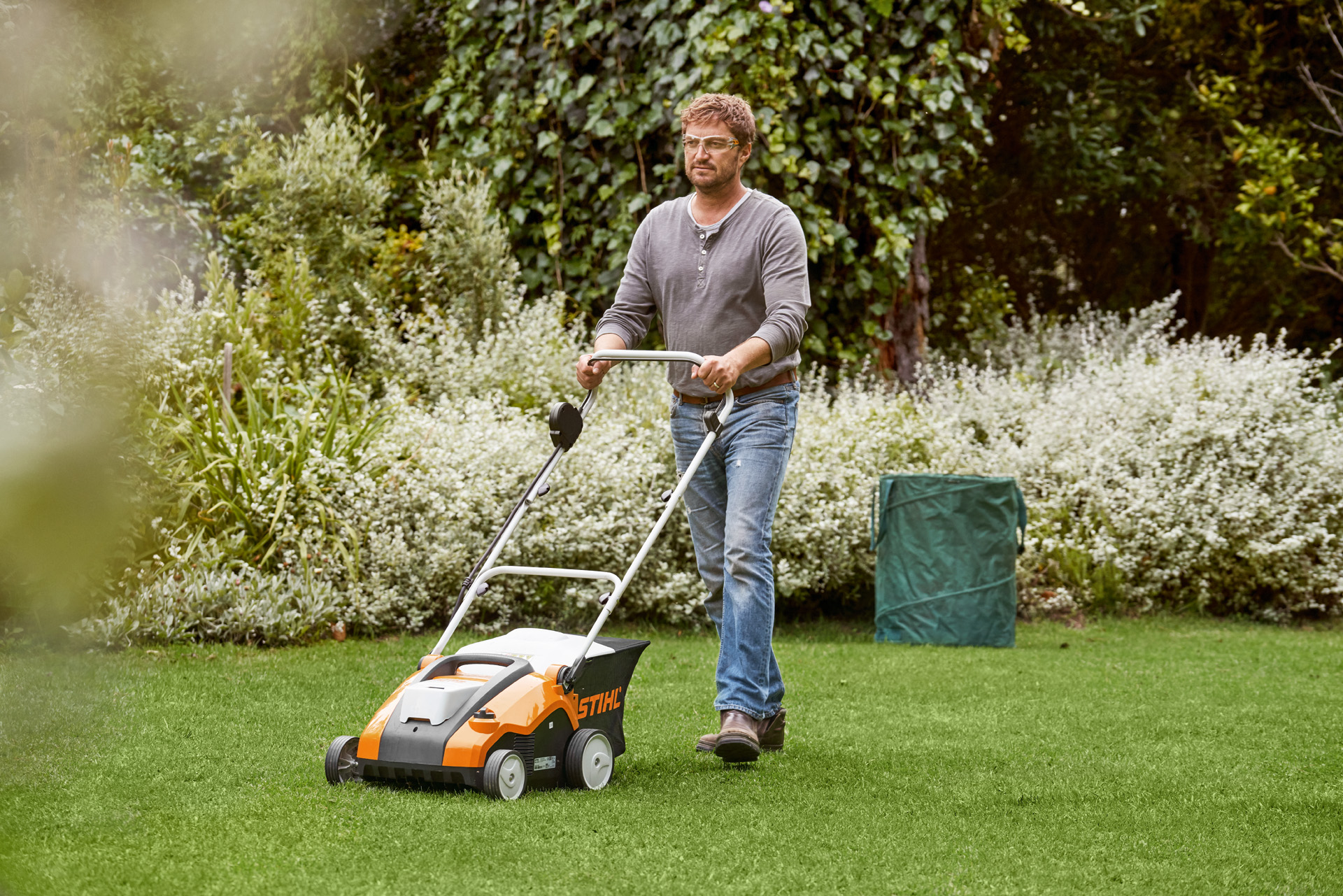 Muž provádí vertikutaci zeleného trávníku pomocí akumulátorového provzdušňovače STIHL RLA 240