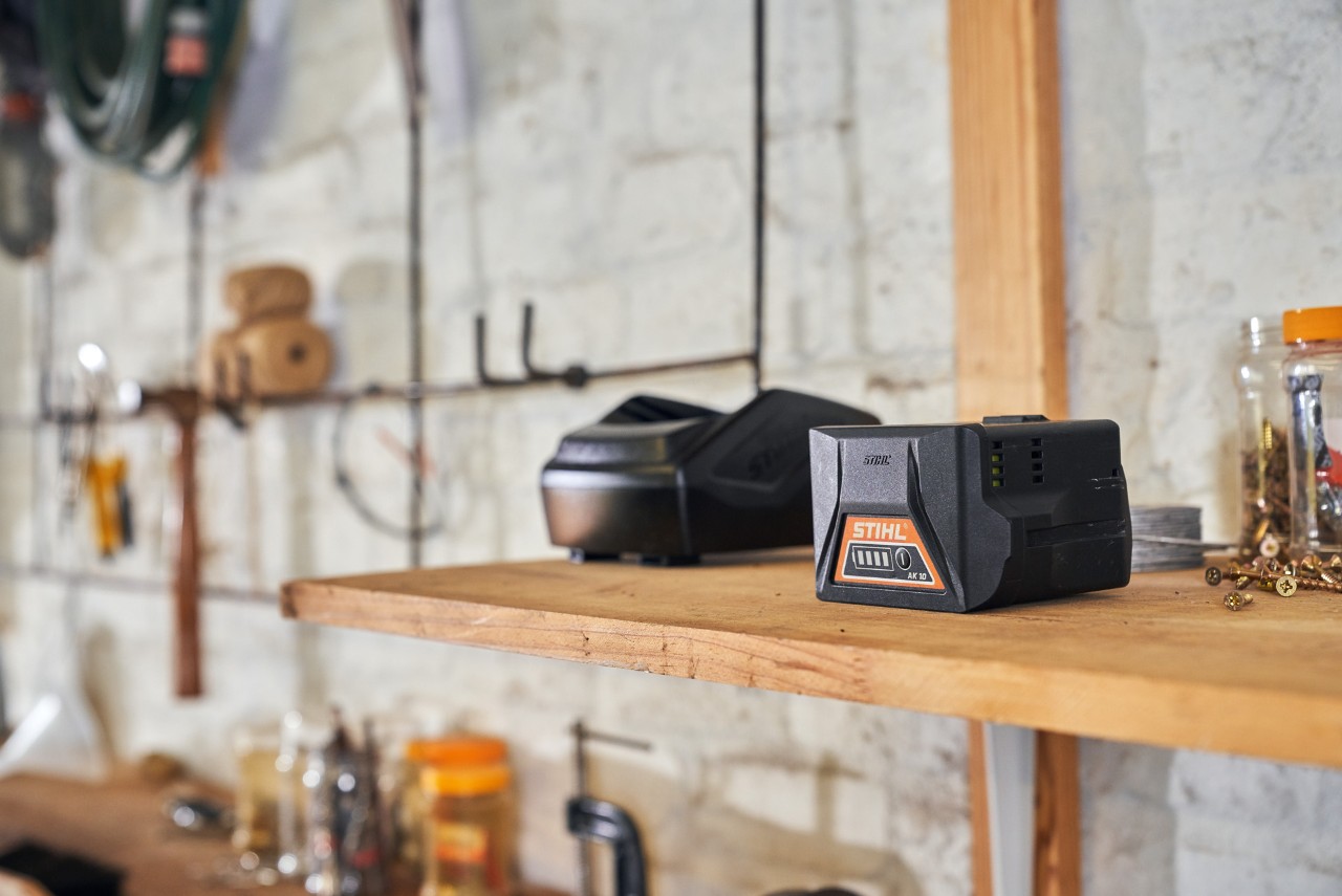Two batteries with STIHL battery technology are lying on a shelf in a workshop