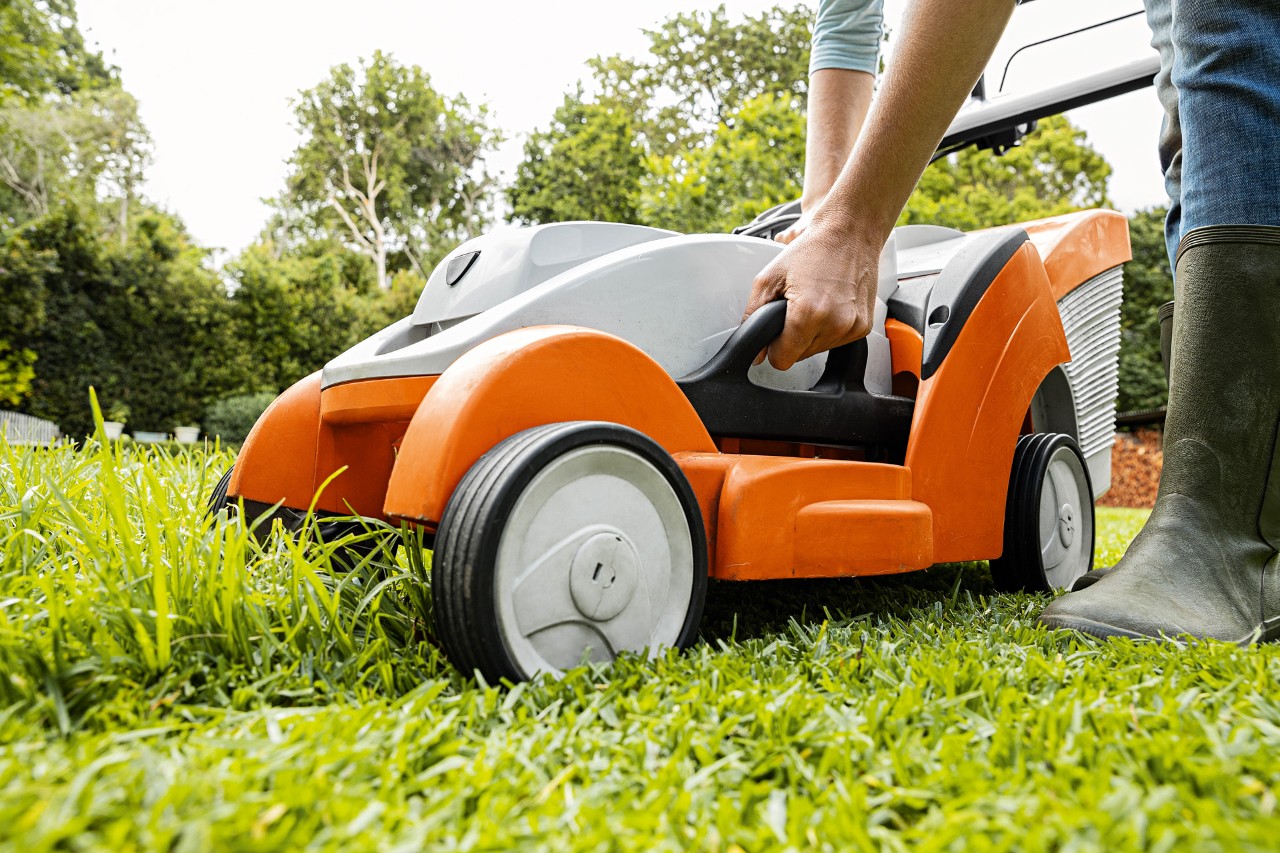 Žena nastavuje výšku sečení na akumulátorové sekačce STIHL RMA 339 C.