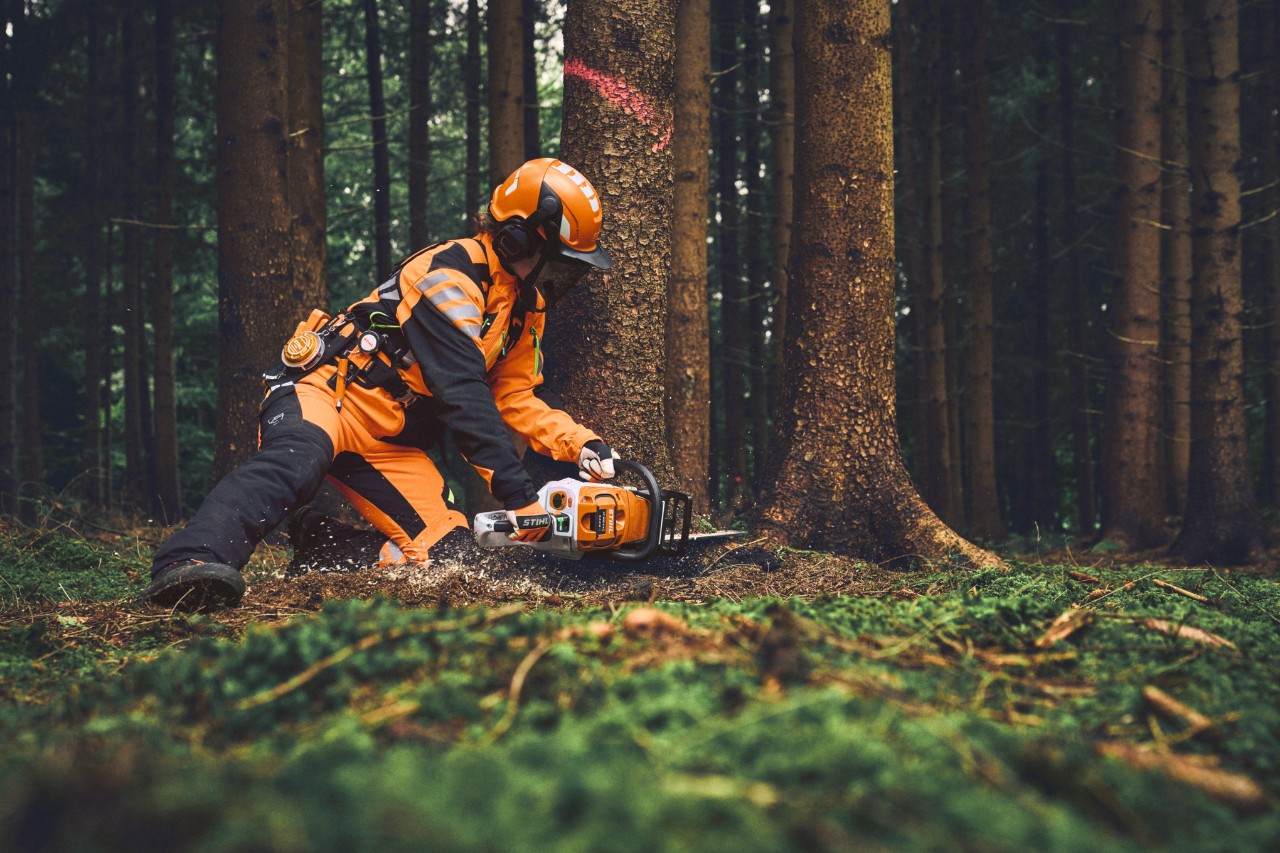 Lesní dělník v ochranném pracovním oděvu STIHL ADVANCE FlexTEC ShellTEC kácí strom motorovou pilou STIHL.