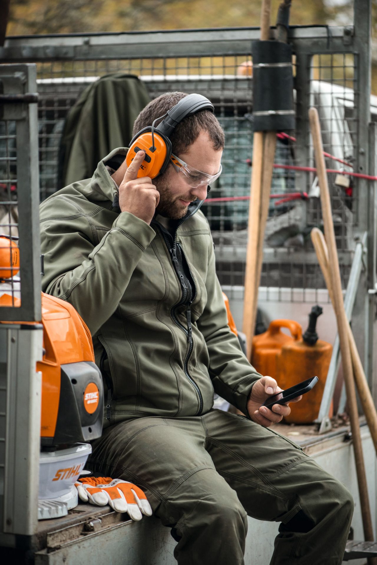 Detailní záběr na přilbovou soupravu STIHL ADVANCE X-Vent ProCOM položenou na kmeni stromu.